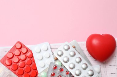 Pembe arka planda haplar, tabletler ve steteskop, üst görünüm