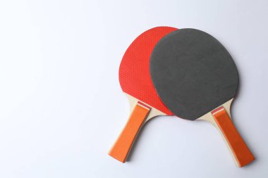 Beyaz zemin üzerinde top olan ping pong raketleri