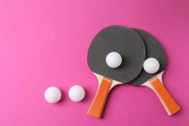 Siyah raket ve topların üst görüntüsü, raketler ve pembe masa üzerinde tenis raketleri. düz yat