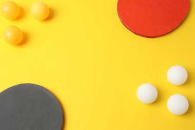 Renkli tenis topları ve sarı arka planda tenis raketleri, düz yatış. metin için boşluk kopyala