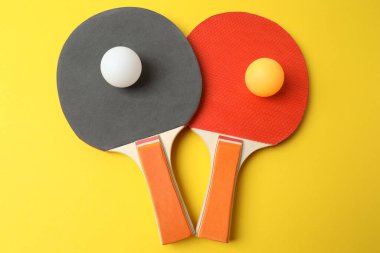 Tenis raketleri ve toplar sarı arka planda