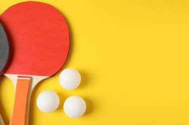 Masa tenisi seti ve topları sarı arka planda, düz yatıyordu. Metin için boşluk