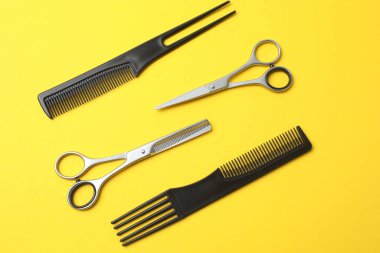 Kuaför aletleri, saç kesimi ve tarağı sarı arka planda izole edilmiş..