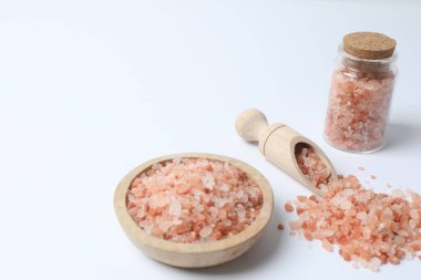 Beyaz arka planda ahşap kaşıkta tuz ve biber.