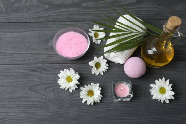 Siyah arka planda pembe çiçekli spa ürünleri ve banyo tuzu.