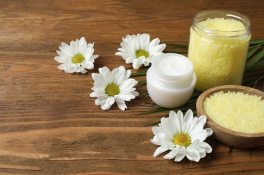 Ahşap arka planda doğal kozmetik ürünleri ve papatya çiçeği