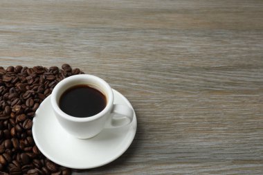 Kahve fincanı ve fasulye ahşap masada..