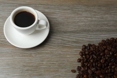 Ahşap arka planda kahve fincanı ve kahve çekirdeği.