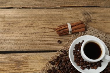 Kahve fincanı, kahve çekirdekleri, tarçın çubukları ve ahşap masada anason yıldızı.