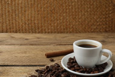 Tarçınlı sade kahve ve ahşap arka planda kahve çekirdekleri.