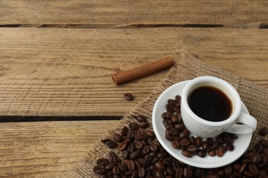 Bir fincan kahve ve kahve çekirdeği ahşap bir masada.