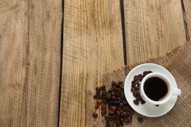 Tahta bir masada bir fincan kahve ve fasulye. Üst Manzara. Boşluğu kopyala.