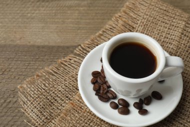 Eski ahşap masanın üzerinde kahve çekirdeği olan bir fincan kahve..