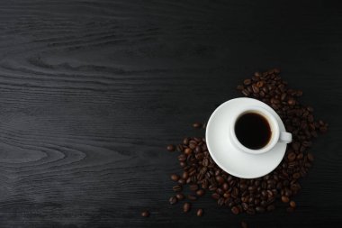 Kahve fincanı ve kahve çekirdekleri masanın üstünde. Kopyalama alanı olan üst görünüm