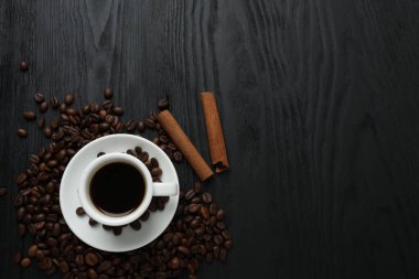 Ahşap bir masada kahve fincanı. Kopyalama alanı olan üst görünüm. Sade kahve fincanı, tarçın çubukları ve anason yıldızlı düz bir kompozisyon.