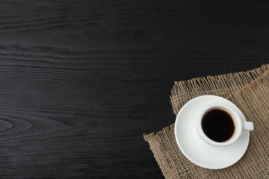 Ahşap arka planda bir fincan kahve ve kahve çekirdeği.