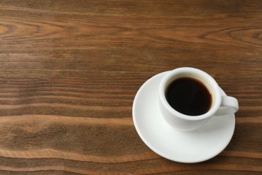 Ahşap arka planda bir fincan sade kahve, üst manzara.