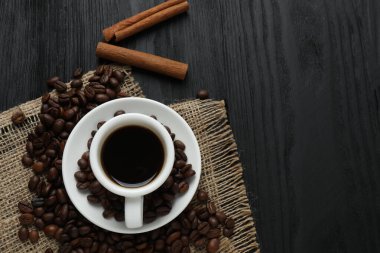 Tarçın çubuklu bir fincan kahve ve ahşap arka planda anason.