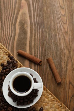 Kahve fincanı, ahşap masa üzerinde kahve çekirdekleri.