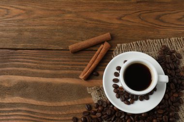 Tarçınlı bir fincan sıcak kahve ve ahşap arka planda anason. Boşluğu kopyala.