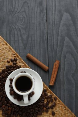 Tahta masada kahve çekirdekleri olan bir fincan sıcak içecek.