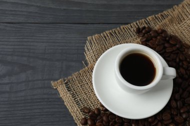 Kahve fincanı ve ahşap masada kahve çekirdeği..