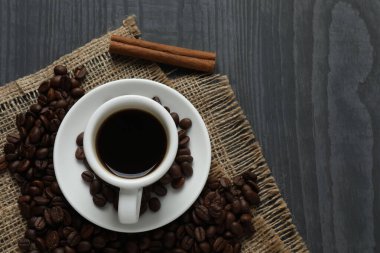 Bir fincan kahve, tarçın ve ahşap arka planda fasulye..