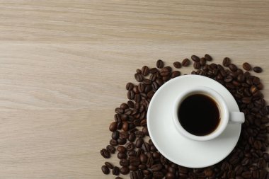 Kahve fincanı ve kahve çekirdekleri ahşap arka planda