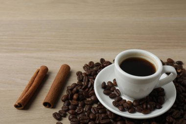 kahve çekirdekleri ve bir fincan kahve beyaz tahta bir masada.