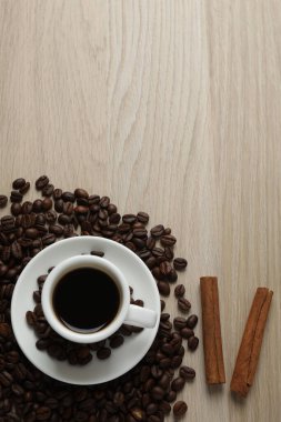Kahve çekirdekli kahve fincanı ve ahşap masada tarçın çubukları, fotokopi alanı olan üst manzara.