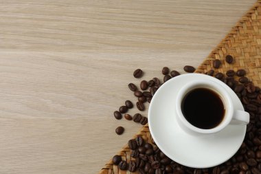 Tahta bir masada bir fincan kahve. Kahve çekirdekleri ve bir fincan kahve..