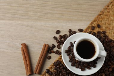 Beyaz ahşap arka planda kahve fincanı ve kahve çekirdeği.