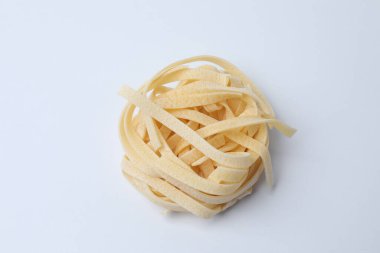 Beyaz arka planda beyaz bir tabakta pişmemiş spagetti. Üst manzara, düz yatış, genel giderler..