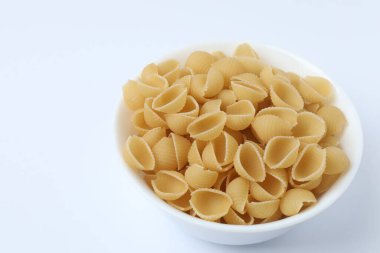 Beyaz arka planda beyaz kasede pişmemiş makarna.