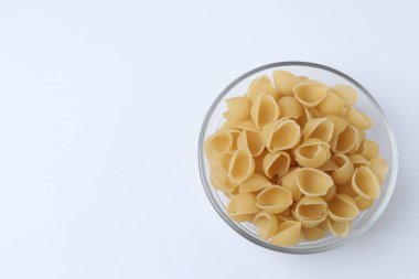 Beyaz arka planda izole edilmiş bir kasede pişmemiş İtalyan makarnası.