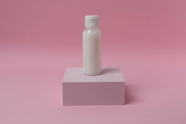 Pembe arka planda beyaz kozmetik şişesi ve mesaj için bir yer..