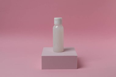 Pembe arka planda bir şişe kozmetik kremi..