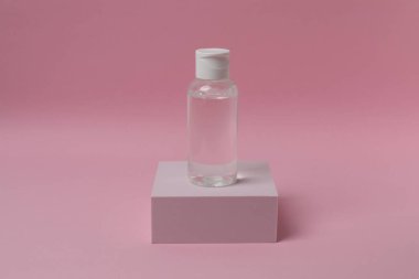 Pembe pastel arka planda pembe bir serum şişesi. asgari güzellik ürünü