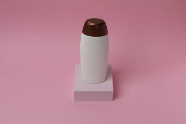 Pembe arkaplanda boş bir krem şişesi, metin için boş yeri olan düz bir yatak.