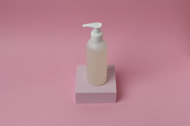 Pembe arka planda boş etiketli kozmetik şişesi.