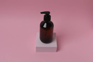 Pembe arka planda bir şişe şampuan.