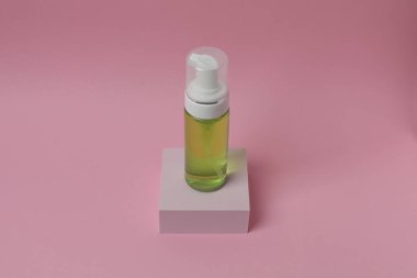 Renkli arka planda cam bir şişede kozmetik serumu..