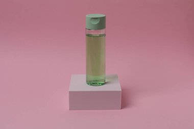 Pembe arka planda parfüm şişesi.