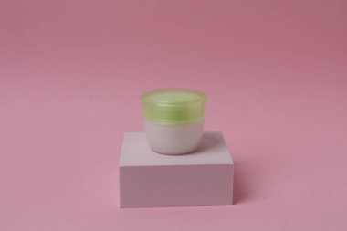 Pastel pembe arka planda bir şişe krema. minimalizm