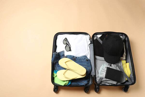 suitcase with different clothes on floor against light background, top view. travel concept