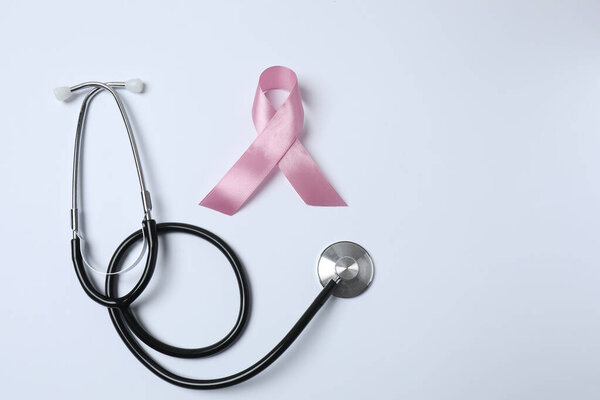 stethoscope with pink ribbon on light background. space for text
