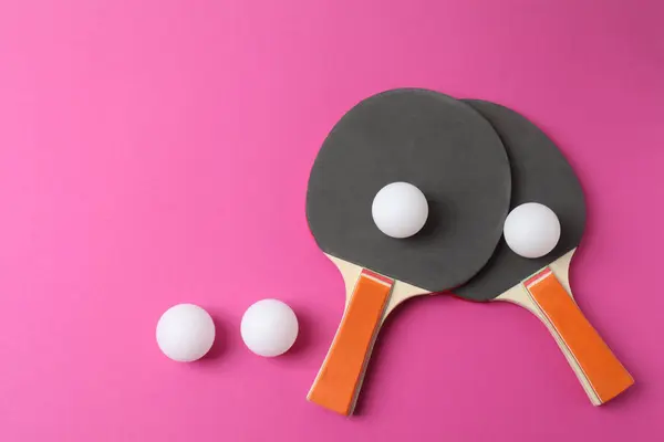 Siyah raket ve topların üst görüntüsü, raketler ve pembe masa üzerinde tenis raketleri. düz yat