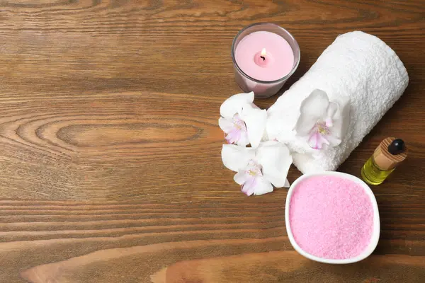 Pembe çiçekli spa kompozisyonu, havlular ve ahşap arka planda mum. Metin için boşluk