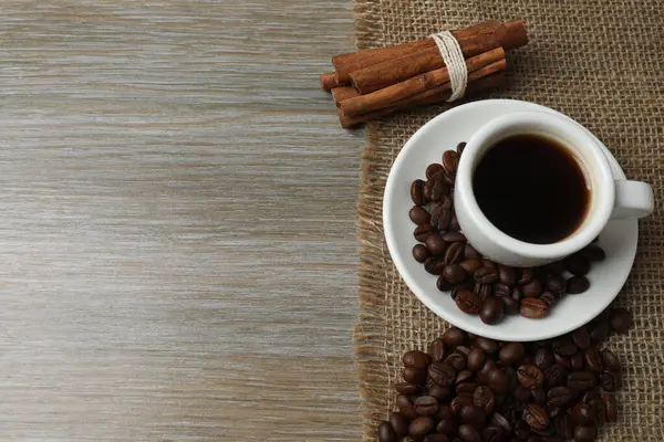 Tarçın çubuklu bir fincan kahve ve ahşap arka planda anason yıldızı..