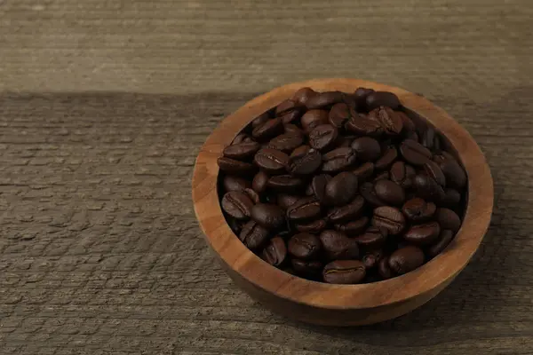Ahşap arka planda, tahtadan bir kasede kahve çekirdeği.